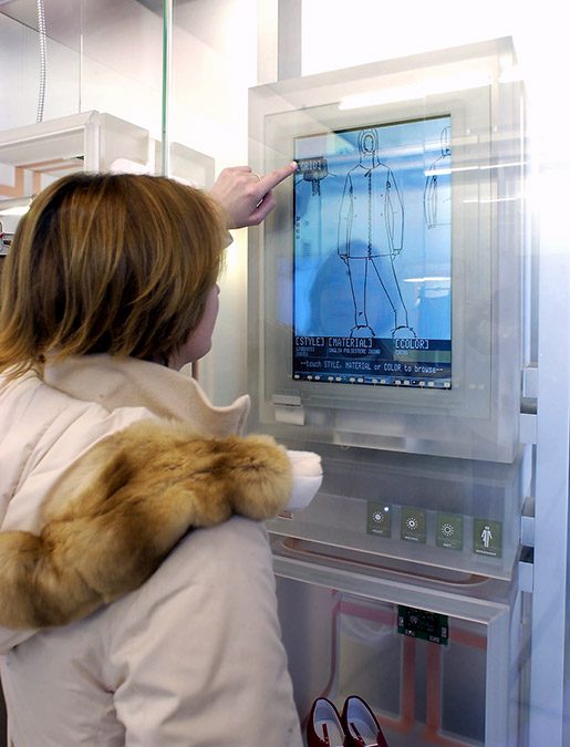 A woman in white jacket touching screen on atm machine.